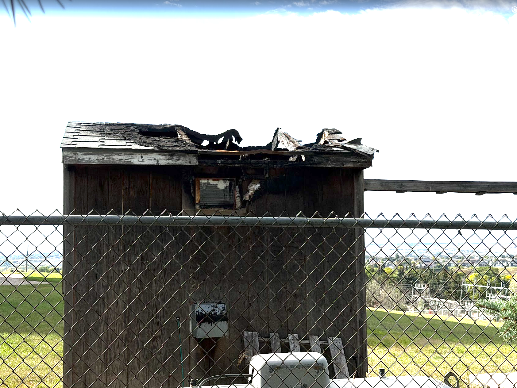 The repeater shack after the 2025 roof fire — the roof is destroyed, the AC unit that caused the fire still visible in the charred wall